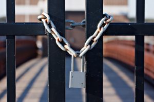 A padlock and chain wrapped around a black fence